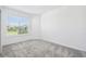 Bright bedroom with plush gray carpet flooring and a large window overlooking the front yard at 4219 Big Sky Dr, Spring Hill, FL 34604