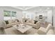 Bright and airy living room featuring two sofas, large windows, and an open floor plan leading to the kitchen at 4219 Big Sky Dr, Spring Hill, FL 34604