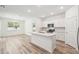 Open-concept living space with wood-look floors, a kitchen island, and plenty of natural light from windows at 4219 Big Sky Dr, Spring Hill, FL 34604