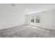 A light-filled bedroom features soft gray carpet, two windows with beautiful views, and is ready to be designed and decorated at 4227 Big Sky Dr, Spring Hill, FL 34604