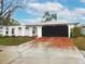 Charming single-Gathering home with a freshly painted exterior and a red stained driveway leading to the garage at 6718 Ranchwood Loop, New Port Richey, FL 34653