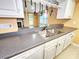 Double sink featuring gray countertops, white cabinets, and view of the connecting living room at 6718 Ranchwood Loop, New Port Richey, FL 34653