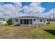 An exterior view of the home's backyard, featuring a screened-in porch, and a grassy lawn at 702 W Brockton Pl # 2, Sun City Center, FL 33573