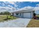 Single-story home with a one car garage, manicured lawn, and a light blue driveway at 702 W Brockton Pl # 2, Sun City Center, FL 33573