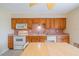 Kitchen with tiled floors, eat in area, wood cabinets, and white appliances at 702 W Brockton Pl # 2, Sun City Center, FL 33573