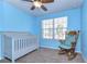 Bedroom featuring carpeted floors, a crib, rocking chair, and window with blinds at 11117 Abaco Island Ave, Riverview, FL 33579