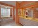 Bright bathroom featuring double sinks, tiled floors, and a large glass block window over a soaking tub at 1875 Oak Branch Dr, Sarasota, FL 34232