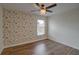 This bedroom has wood floors, fan, and a window with floral wallpaper accent at 1875 Oak Branch Dr, Sarasota, FL 34232