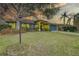 A light pole in front of the house, featuring a vibrant yellow exterior, a blue front door, and colorful landscaping at 1875 Oak Branch Dr, Sarasota, FL 34232