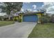 A bright yellow single-story house with a blue garage door and meticulously kept grass and landscaping at 1875 Oak Branch Dr, Sarasota, FL 34232