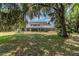 Expansive backyard with lush green grass, mature trees, and a screened pool enclosure at 1902 Sweet Bay Ct, Plant City, FL 33566