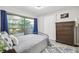Bedroom with large window, blue curtains, wood dresser, and blue and white area rug at 1902 Sweet Bay Ct, Plant City, FL 33566