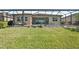 Wide backyard featuring a screened-in patio with pool, seating, and green grass at 20237 Bandera Pl, Venice, FL 34293