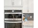 Close up of oven and microwave in the kitchen with white cabinets and tile backsplash at 20237 Bandera Pl, Venice, FL 34293