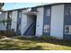 Two-story condo with blue trim, lush landscaping, and a staircase leading to the upper units at 256 Cypress Ln # 120, Oldsmar, FL 34677