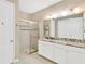 Well-lit bathroom with a glass-enclosed shower, granite countertop, double sinks, and ample storage in the white cabinets at 4071 Balcony Breeze Dr, Land O Lakes, FL 34638