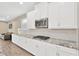 Stylish kitchen with granite countertops, stainless steel microwave and white cabinets, next to the living area at 4071 Balcony Breeze Dr, Land O Lakes, FL 34638