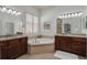 Bright bathroom featuring dual vanities, soaking tub, and plantation shutters at 4946 Sapphire Sound Dr, Wimauma, FL 33598