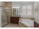 Light-filled bathroom with a glass shower and a soaking tub with tile surround at 4946 Sapphire Sound Dr, Wimauma, FL 33598