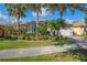 Charming single-story home featuring lush landscaping with palm trees and a well-manicured lawn at 4946 Sapphire Sound Dr, Wimauma, FL 33598