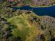 Aerial view showcases a sports field alongside a tranquil lake with a dock in a lush, green community at 9101 Highland Ridge Way, Tampa, FL 33647