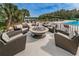Outdoor seating area with a stone fire pit surrounded by comfortable wicker chairs at 9101 Highland Ridge Way, Tampa, FL 33647