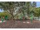 Community playground featuring swings and climbing structures set within a mulched area, shaded by mature trees at 9101 Highland Ridge Way, Tampa, FL 33647
