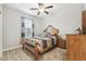 Cozy bedroom features a wooden bed frame, ceiling fan, and natural light from the window at 9645 Little Bluestem Dr, Land O Lakes, FL 34637