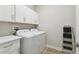 Well-lit laundry room includes white appliances, cabinets, and a convenient ladder for storage at 9645 Little Bluestem Dr, Land O Lakes, FL 34637