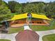 Aerial view of playground with swings and a seesaw under a yellow shade at 9645 Little Bluestem Dr, Land O Lakes, FL 34637