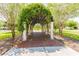 A beautiful walkway with an arched trellis covered in greenery, leading to a peaceful park area at 9645 Little Bluestem Dr, Land O Lakes, FL 34637
