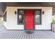 Welcoming front entrance with a striking red door, grey porch, modern lighting, and elegant windows at 32608 Knollwood Ln, Wesley Chapel, FL 33545