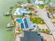 Stunning aerial view of a waterfront home with a pool, private dock, and solar panels, surrounded by lush landscaping and water views at 7984 1St S Ave, St Petersburg, FL 33707