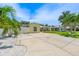 Long, paved driveway and lush landscaping leading to a yellow home with a well-maintained lawn at 7984 1St S Ave, St Petersburg, FL 33707
