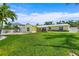 Charming yellow home featuring a lush green lawn, palm trees, and white picket fence at 7984 1St S Ave, St Petersburg, FL 33707