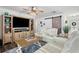 Bright living room with light wood entertainment center, beamed ceiling fan and cozy seating at 7984 1St S Ave, St Petersburg, FL 33707