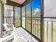 The screened-in balcony offers a peaceful view of a green lawn and trees and features two white chairs at 8174 Terrace Garden N Dr # 307, St Petersburg, FL 33709