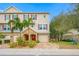 Charming townhouse with a brick driveway, red door, garage, and a manicured, landscaped yard with tropical plants at 876 Callista Cay Loop, Tarpon Springs, FL 34689