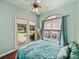 A bedroom features hardwood floors, bright windows, and cozy bedding at 12333 Woodlands Cir, Dade City, FL 33525