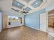 Spacious bedroom with a decorative blue tray ceiling and wood floors with large windows and curtains at 12333 Woodlands Cir, Dade City, FL 33525