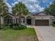 Inviting single-story home featuring a well-manicured lawn, mature palms, and a two-car garage at 12333 Woodlands Cir, Dade City, FL 33525