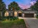 Inviting single-story home featuring a well-manicured lawn, mature palms, and a two-car garage at 12333 Woodlands Cir, Dade City, FL 33525