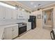 Updated kitchen with white cabinets, stainless steel appliances, and a view of the hallway at 12333 Woodlands Cir, Dade City, FL 33525