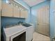 Laundry room with modern washer and dryer, utility sink, storage cabinets, and natural light at 12333 Woodlands Cir, Dade City, FL 33525