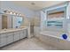 Light-filled bathroom featuring double sinks, a soaking tub, glass block accents, and a blue accent wall at 12333 Woodlands Cir, Dade City, FL 33525