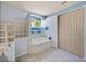 Bathroom with tile floors, a soaking tub, and a glass block window for natural light and privacy at 12333 Woodlands Cir, Dade City, FL 33525