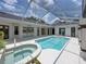 Lush, screened-in pool area featuring a pristine pool and jacuzzi that is perfect for entertaining at 12333 Woodlands Cir, Dade City, FL 33525