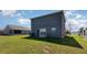 A spacious backyard featuring green grass, a gray house, and a sliding glass door at 1308 22Nd E St, Palmetto, FL 34221
