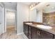 Bathroom featuring double sinks, dark wood cabinets, and tile flooring leading to a walk-in closet at 1308 22Nd E St, Palmetto, FL 34221
