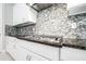 Close up of kitchen cooktop with modern backsplash, granite countertops and white cabinets at 21807 Amelia Rose Way, Land O Lakes, FL 34637